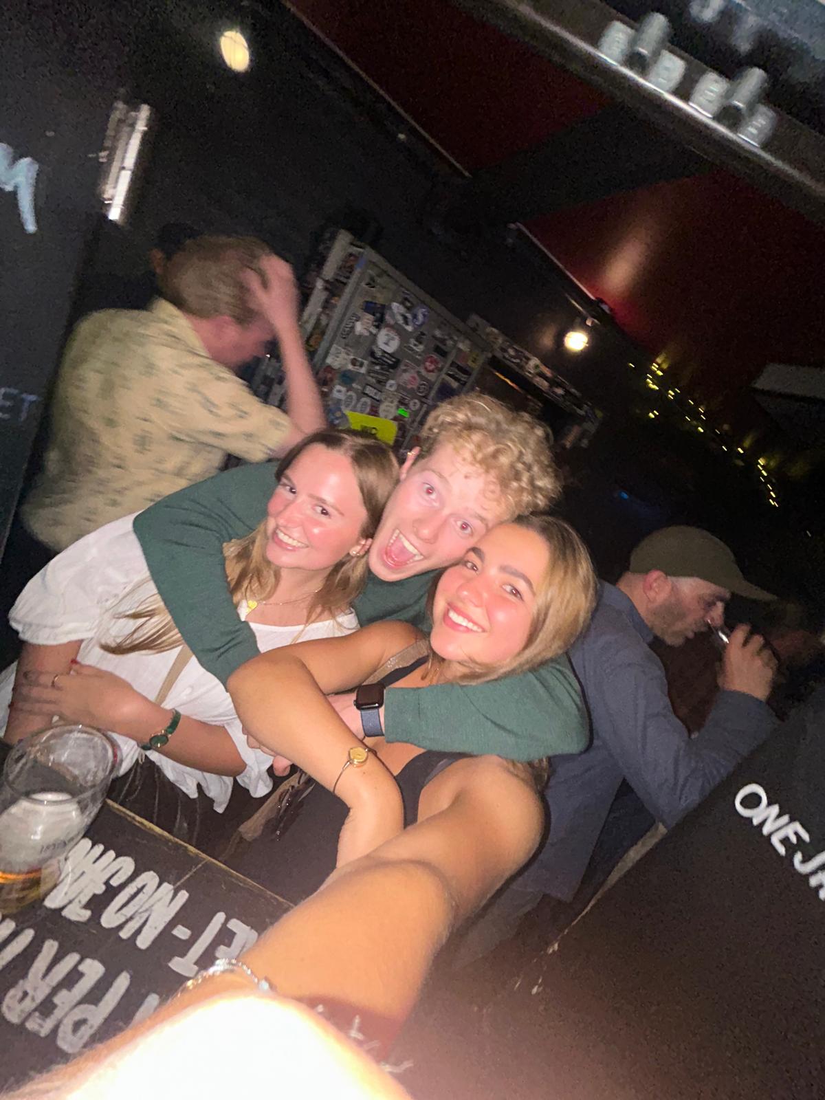 Three friends smiling together at a bar